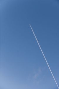 Low angle view of vapor trail against clear blue sky