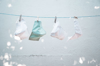 Close-up of clothes drying on clothesline against white wall