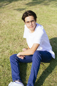 Full length of young man sitting on grass at park