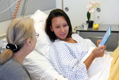 Grandmother and granddaughter using digital tablet in hospital ward