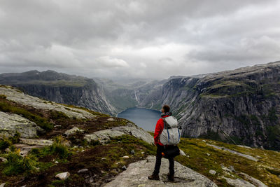 Rear view of man standing on mountain against sky