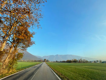 Empty road along landscape and against blue sky