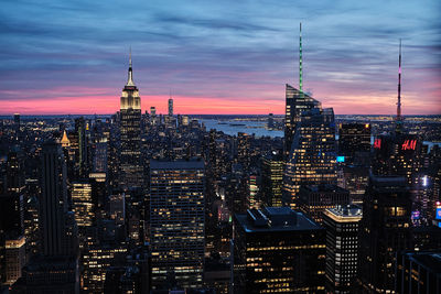 Illuminated buildings in city against sky during sunset