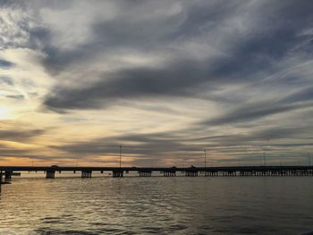 Pier on sea against cloudy sky