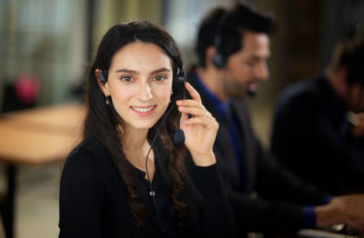 Portrait of smiling young woman with colleagues in background