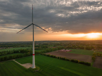 Windmill on field against sky during sunset