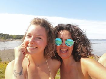 Portrait of smiling mother and daughter against sea