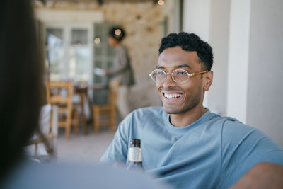 Happy young man talking with woman sitting in patio