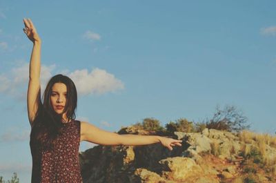 Young woman with arms outstretched standing against blue sky