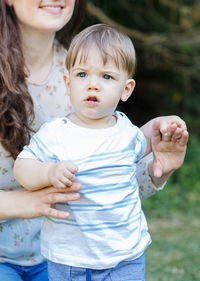 Midsection of mother holding son outdoors