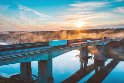 Bridge over river against sky during sunset