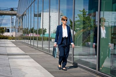 Full length of young woman with umbrella on glass