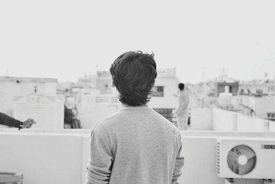 Rear view of man standing against clear sky