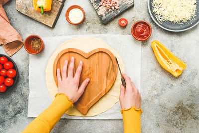 Hands of a caucasian teenage girl in an apron cut out the dough 