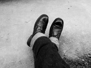 Low section of man wearing shoes while sitting outdoors