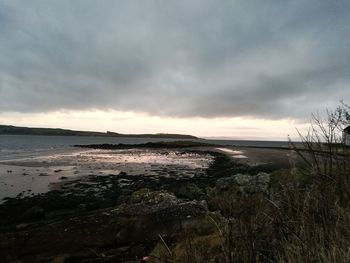 Scenic view of beach against dramatic sky