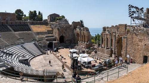 Tourists exploring old ruins of ancient greek theater during summer vacation