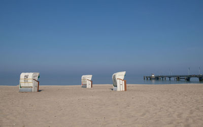 Deck chairs on beach against clear blue sky