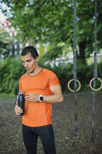 Man holding bottle while standing at park