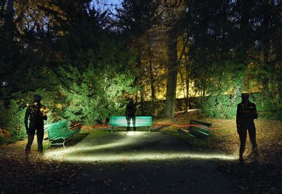 Rear view of people walking on street amidst trees