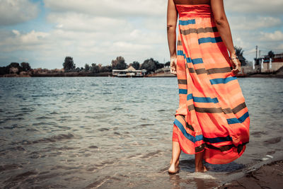 Unrecognizable woman walking through shallow water at the beach.