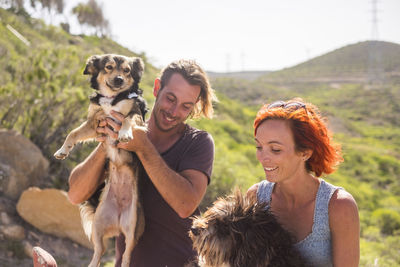 Happy couple with dogs against mountain