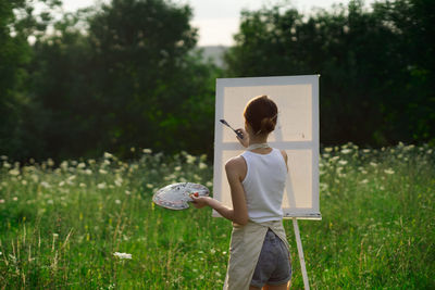 Rear view of woman holding umbrella on field