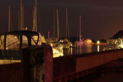 Sailboats moored at harbor against sky at night