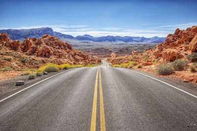 Road leading towards mountains against sky