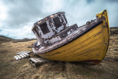 Abandoned boat moored against sky
