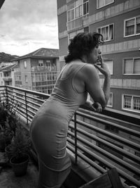 Side view of woman in balcony against buildings in city