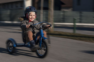 Portrait of boy riding motor scooter on road