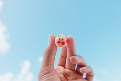 Close-up of person holding hand against sky