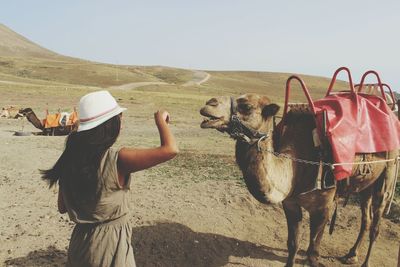 Woman with camel standing on sand