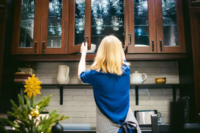 Woman taking bowl from kitchen cabinet