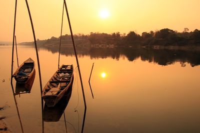 Sailboats moored on lake against sky during sunset