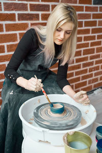 Full length of woman holding ice cream against brick wall