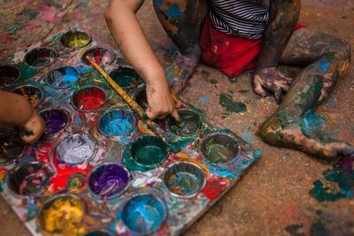 Low section of child playing with paint on a tray on te floor