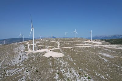 Wind turbines on land against clear sky