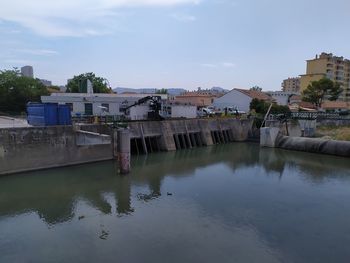 Bridge over river by buildings against sky