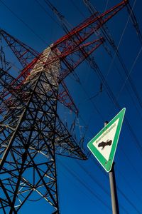 Low angle view of electricity pylon against clear blue sky during sunny day