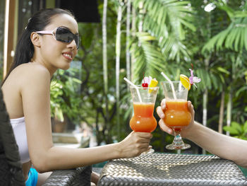 Side view of smiling young woman holding drink