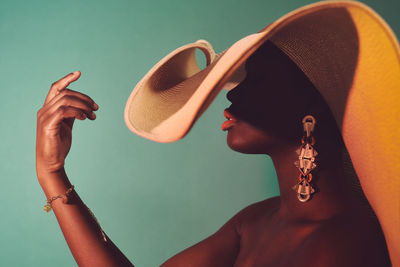 Midsection of black woman wearing large sun hat and statement earrings