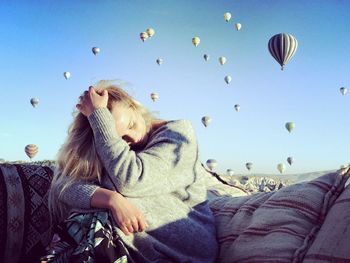 Woman sitting against hot air balloons