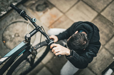 A young man holds the handlebars of a bicycle with his hand.