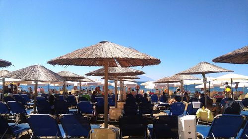 Group of people in restaurant at beach against clear blue sky