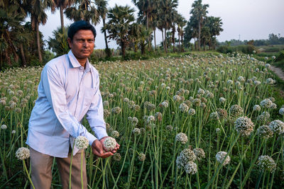 Portrait of man standing amidst purple flowering plants