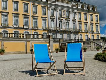 Empty chairs on street by building