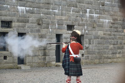 Rear view of man standing against brick wall