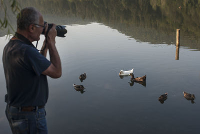 Young man photographing birds on a lake